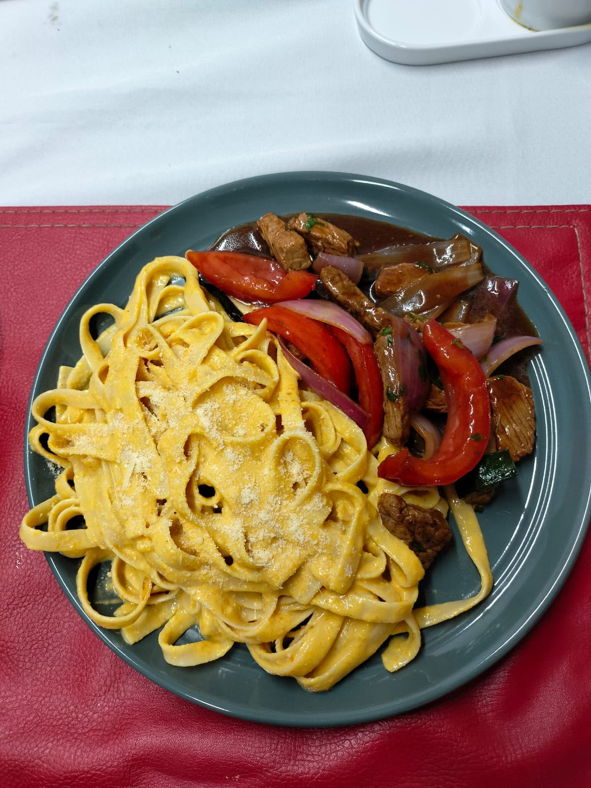 Fetuccini en salsa huancaína junto a lomo salteado con tomate y cebolla, preparado en WOK-TON